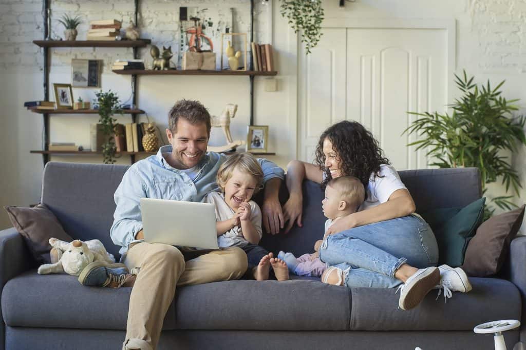 A family sitting on a couch with a laptop.