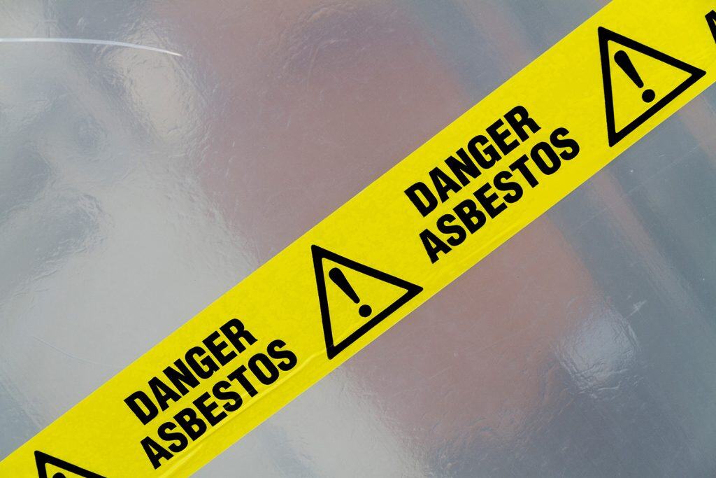 A yellow and black sign with the words danger asbestosos.