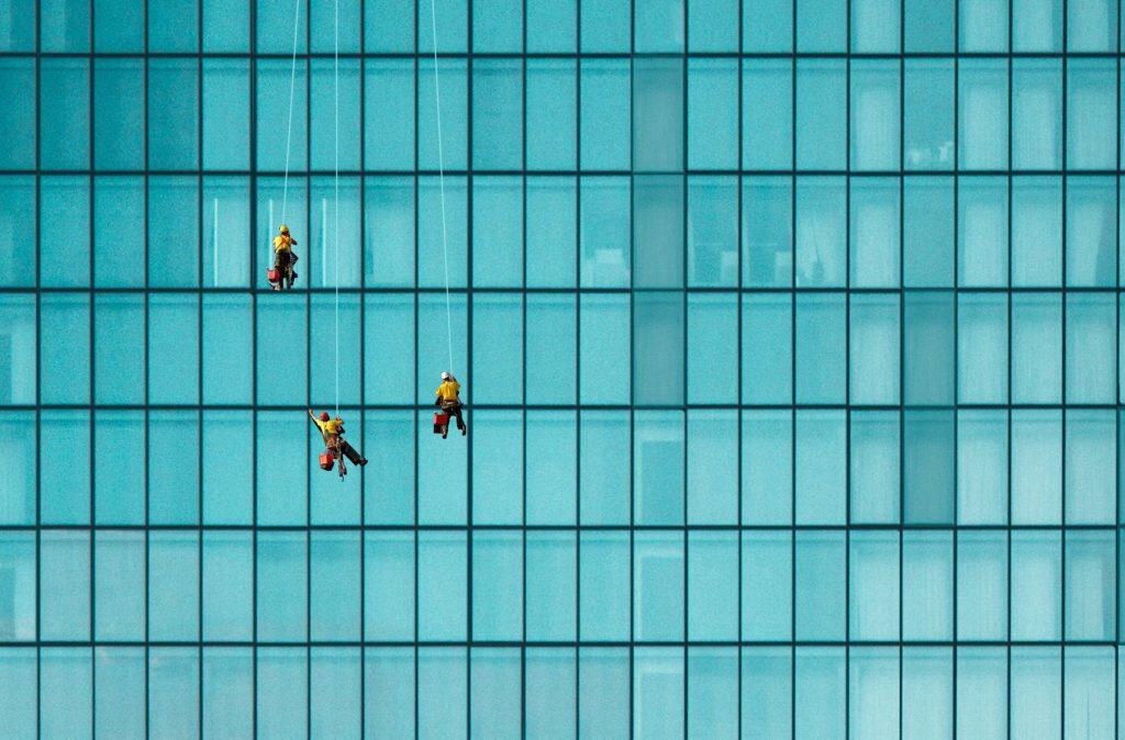Three men are cleaning windows on a building.